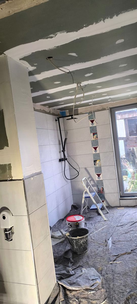 Płytki na ścianach – Płytki ścienne z pasem dekoracyjnym w strefie prysznica, montaż deszczownicy, szpachlowanie sufitu.