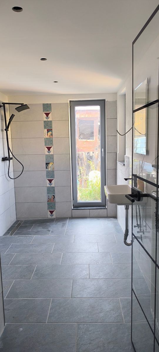Gotowe: prysznic bez brodzika – Prysznic typu walk-in z odpływem liniowym, grafitowe płytki na podłodze, umywalka i drzwi ze szkła.